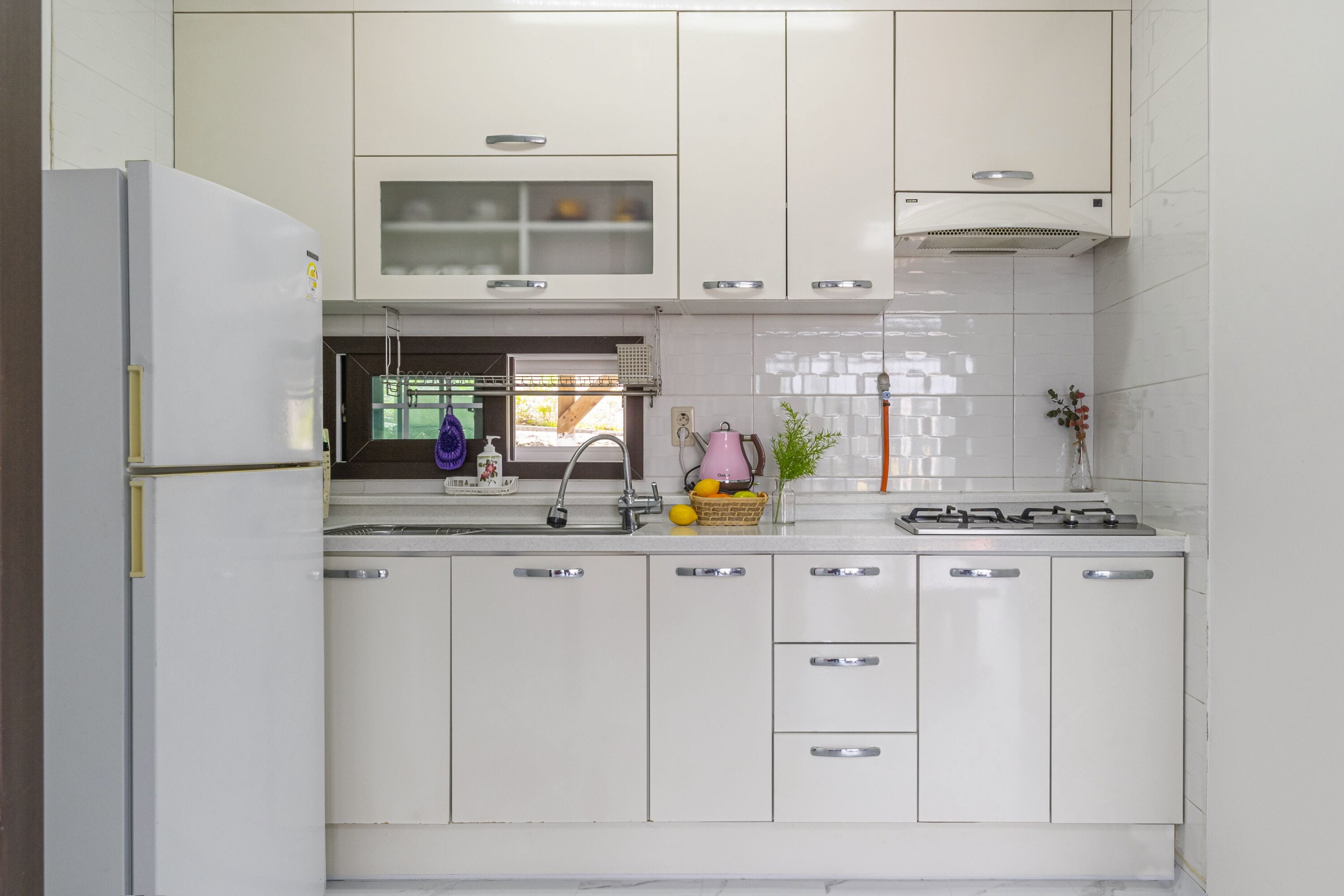 A modern kitchen with white cabinets, a built-in stove, and a sink.