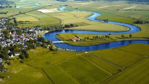An aerial view of a rural landscape with a winding river, fields, and a small village.