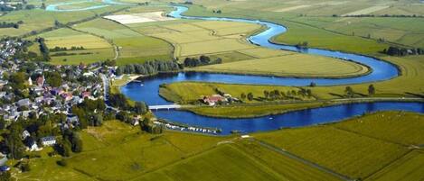 An aerial view of a rural landscape with a winding river, fields, and a small village.