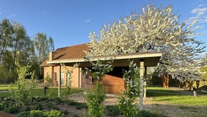 Un bâtiment à la façade en briques, doté d’un porche abrité et d’un jardin où poussent différentes espèces de plantes.