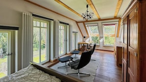 Une pièce avec de grandes fenêtres, un lit, un bureau et une chaise.