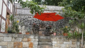 A stone staircase leading to a wooden deck with potted plants and a red umbrella.