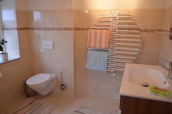 Un baño con inodoro, lavabo y perchero para toallas.