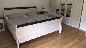 Un dormitorio con cama, mesita de noche, lámpara y un armario con espejo.