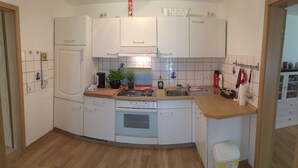 Una cocina compacta con gabinetes blancos, estufa y lavamanos.