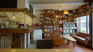 A cozy library with bookshelves, a wooden bar, and seating areas. - Hakuba Station Guest House Hostel eN (Hakuba)