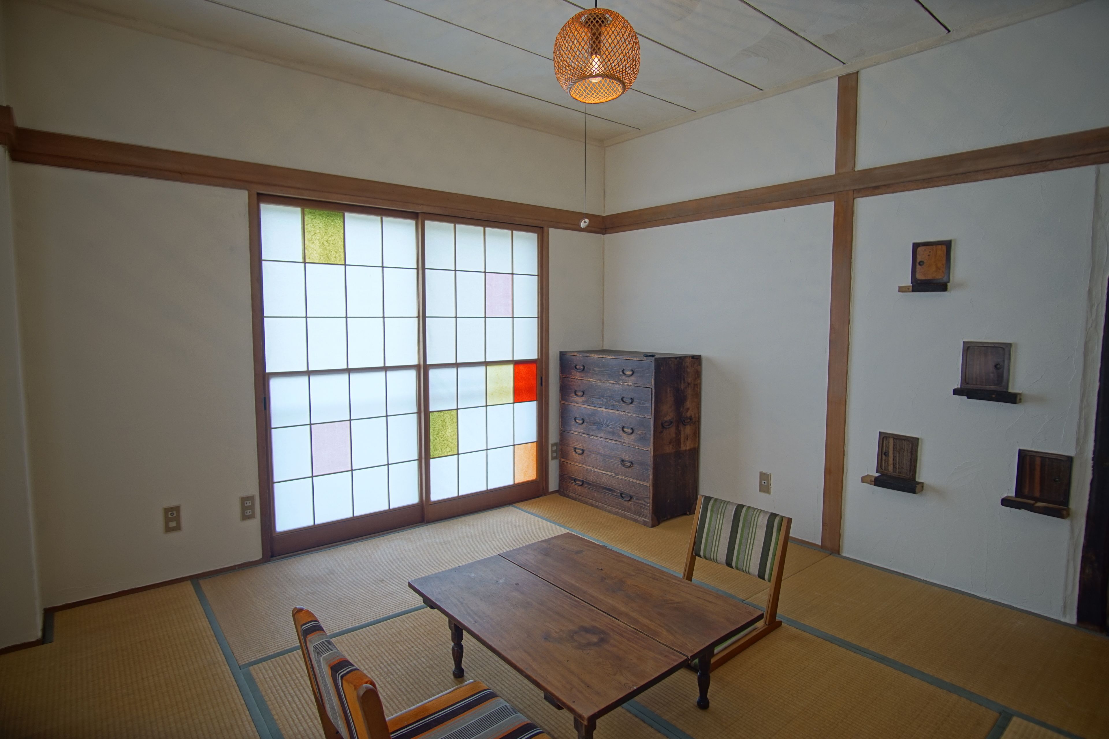 Une pièce de style japonais traditionnel, avec un sol recouvert de tatamis, une table en bois, des portes coulissantes et un meuble.