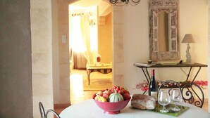 A dining area with a table set for two, featuring a bowl of fruit, a bottle of wine, and two glasses. - Atypical house in the south of Provence near Avignon, 4 persons   (Carpentras)