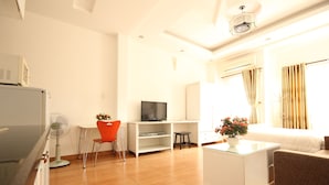 A modern living room with a flat-screen TV, a white coffee table, a red chair, and a sofa. - Smiley Apartment 3 (Ho Chi Minh City)