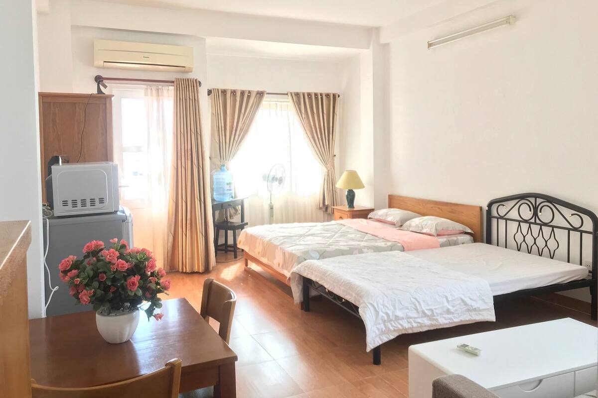 A hotel room with two beds, a desk with a chair, a TV, a water dispenser, and a lamp.