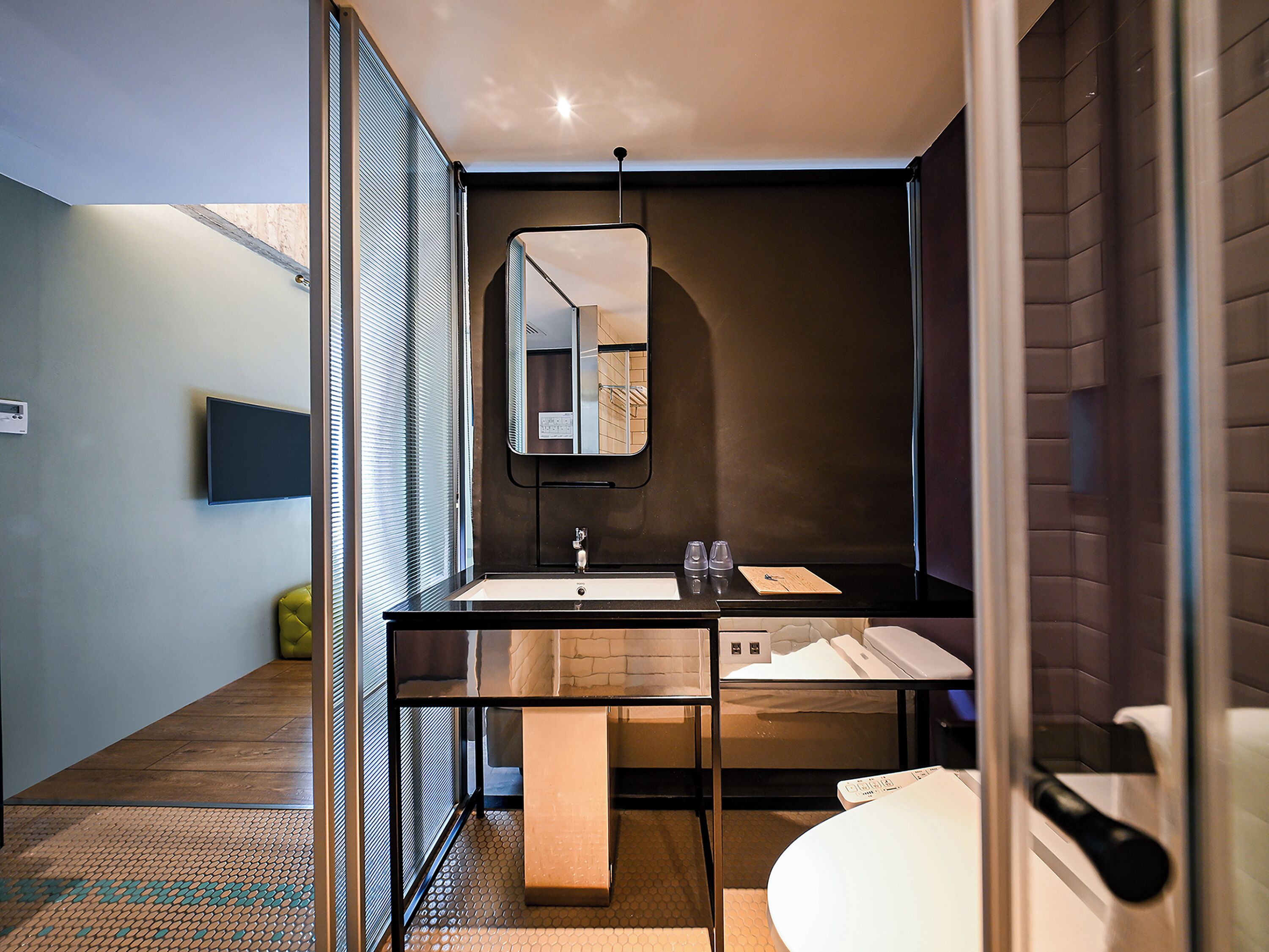 Un bany modern amb un separador de vidre, un lavabo, un mirall i un vàter.
