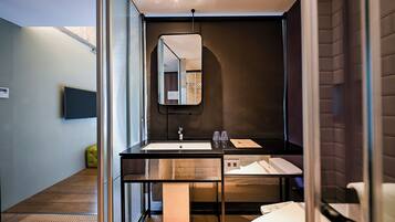 Un bany modern amb un separador de vidre, un lavabo, un mirall i un vàter.