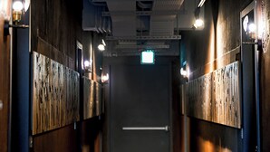 A hallway with wooden paneling, a door at the end, and overhead lighting. - Check inn Hive (Luodong)