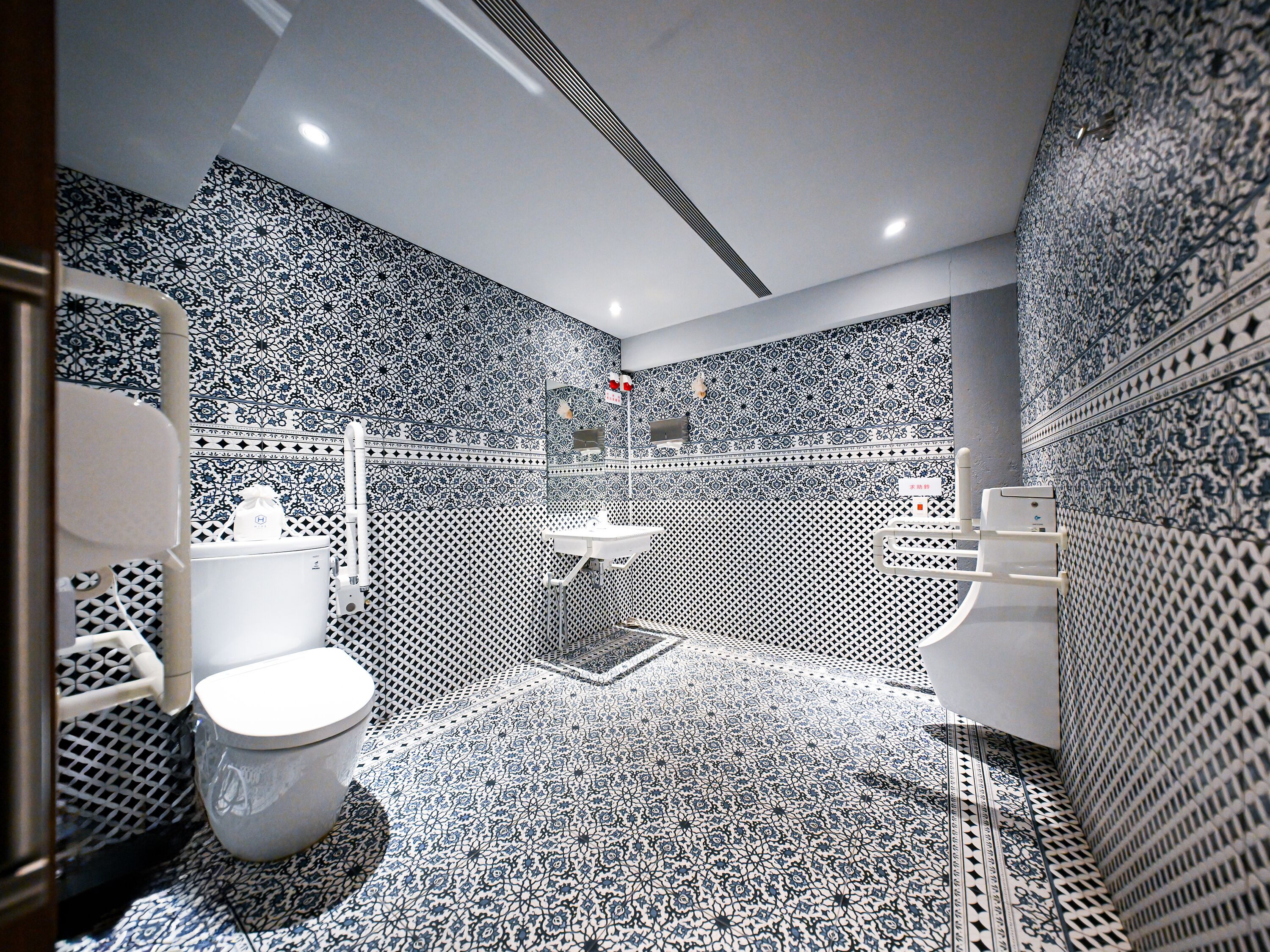 Ein Badezimmer mit gemusterten Fliesen, einer Toilette, einer Duschkabine und einem Waschbecken.