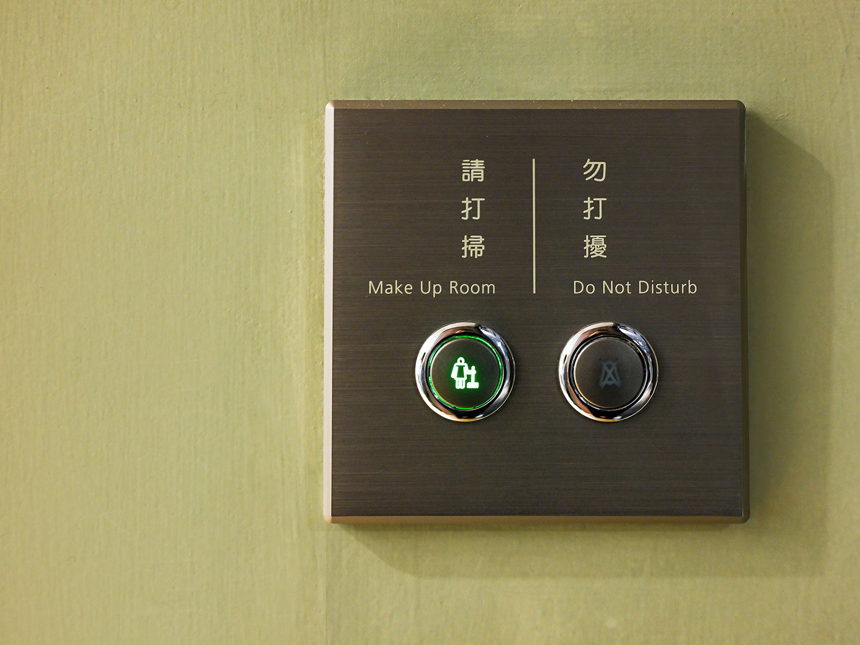 A wall-mounted control panel with two buttons, one labeled 'Make Up Room' and the other 'Do Not Disturb,' accompanied by Chinese characters.