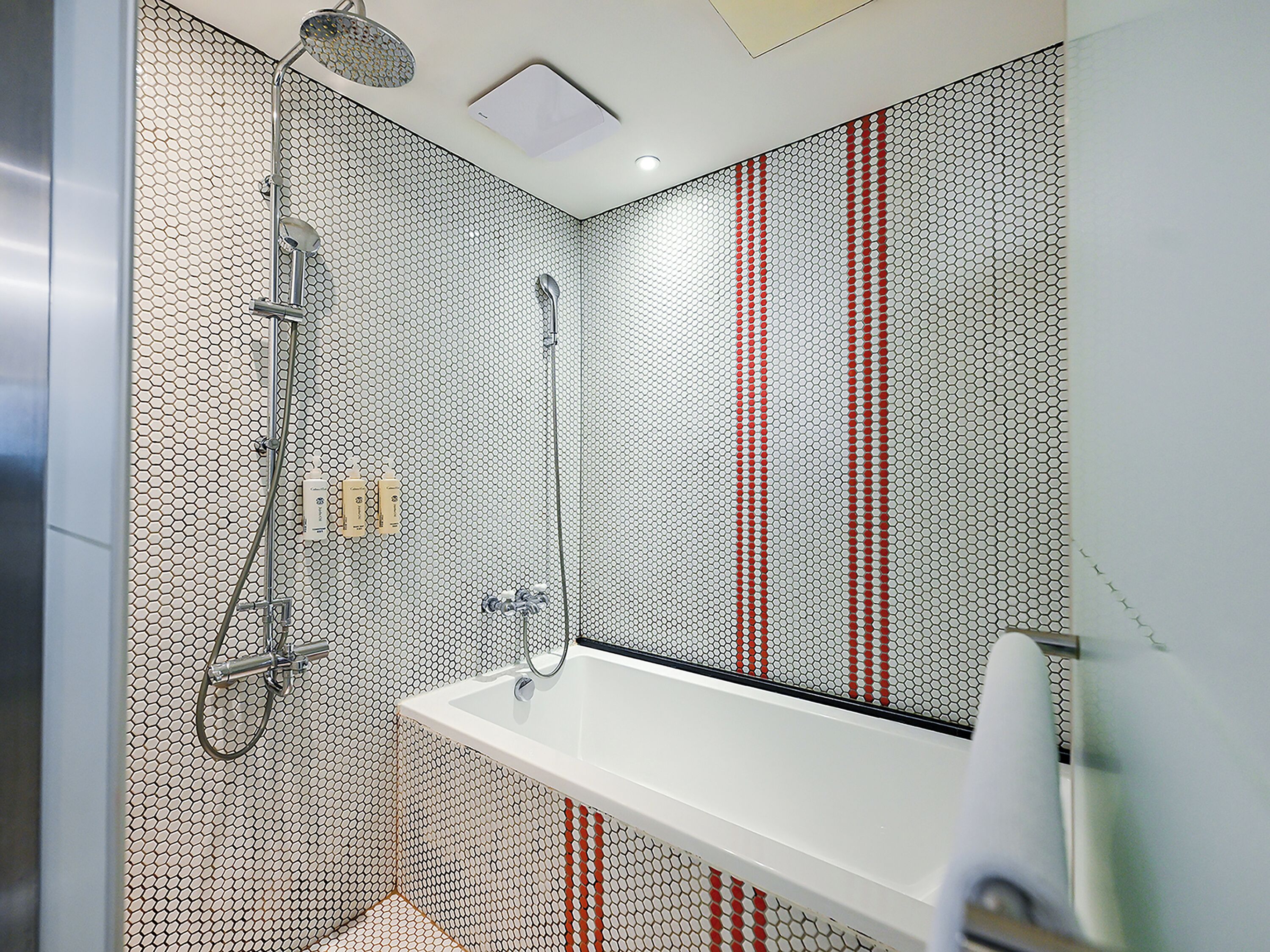 Ein modernes Badezimmer mit einem weißen Waschbecken, einer Dusche mit Regendusche und einer Wand mit Wabenmuster.