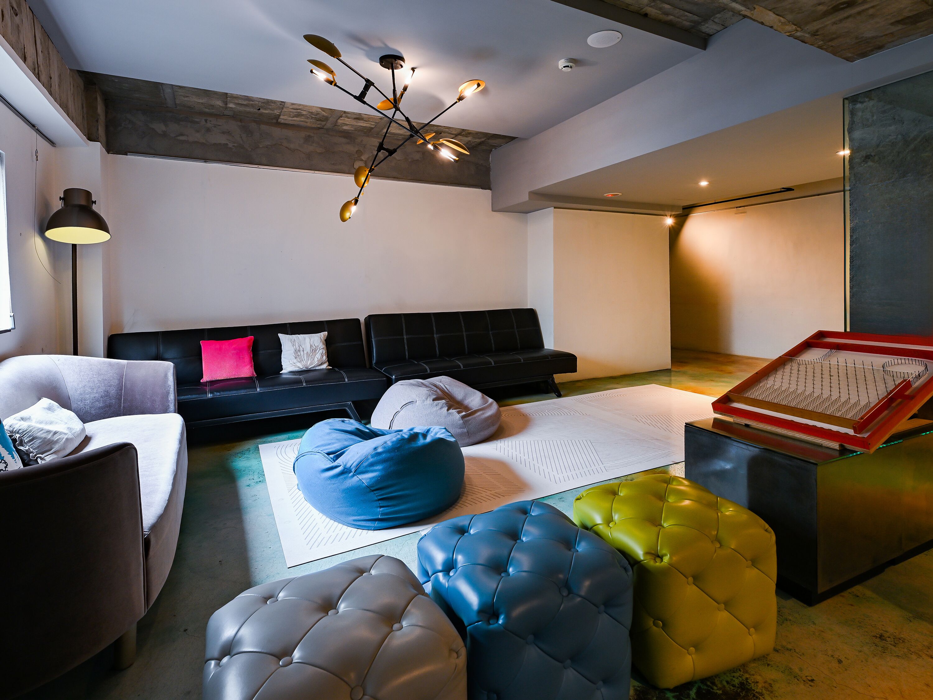 Un salón moderno con un sofá negro, un sillón blanco y un asiento tipo puff azul.