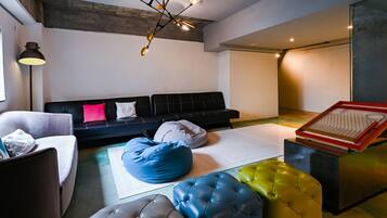 Un salón moderno con un sofá negro, un sillón blanco y un asiento tipo puff azul.