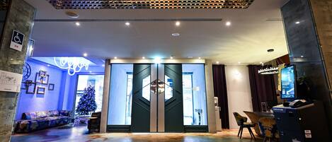 A modern hotel lobby with a check-in counter, a Christmas tree, and a unique ceiling design.