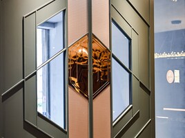 Diseño geométrico de pared con varias ventanas y un elemento hexagonal reflectante central.