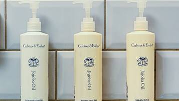 Three bottles of Crabtree & Evelyn products against a tiled wall.