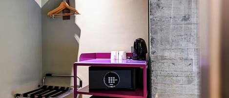 A compact room with a purple storage unit, a black coffee maker, and a foldable chair.