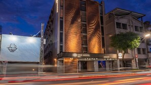 A modern hotel with a distinctive textured facade, a prominent entrance, and a visible sign. - Check inn Hive (Luodong)