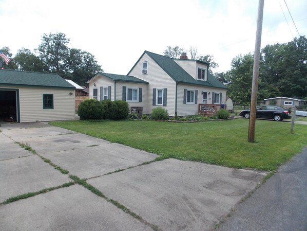 A two-story house with a green roof, a garage, and a front lawn. - Beach Access! Minutes From Cedar Point, Kalahari, Jet Express, And Boat Basin! (Huron)