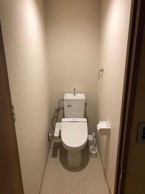 A small, narrow bathroom with a toilet, bidet, and hand dryer. - Rengeso (Tokyo)