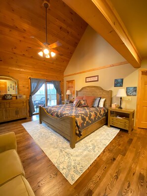 Une chambre confortable avec un plafond en bois, un lit recouvert d’une couvre-lit à motifs, une table de chevet et une commode.