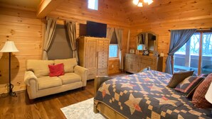 Ein gemütliches Holzhütten-Zimmer mit Bett, Sofa, Kommode und Fenster.