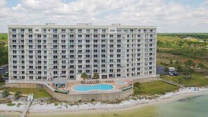 Um hotel grande, com vários andares, área de piscina e vista para a praia.