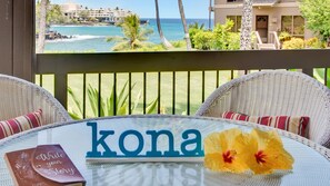 A wicker table with a 'kona' sign and a book titled 'Write your Story'. - Spacious, Ground Floor, Waterfront Condo, Kanaloa at Kona Resort, Central Air (Kailua-Kona)