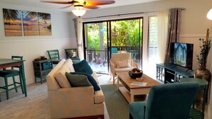 A living room with a sofa, a coffee table, a TV, and a dining area with chairs and a table. - Maui Tranquility ... Relax, Unwind and Feel Welcomed! (Kihei)