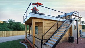 A wooden cabin with a balcony, a staircase, and a fenced yard. - Tiny Home near Zion with Rooftop Stargazing Deck (Orderville)
