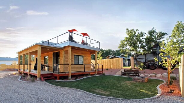 A wooden cabin with a balcony, a gravel driveway, and a lawn. - Tiny Home near Zion with Rooftop Stargazing Deck (Orderville)