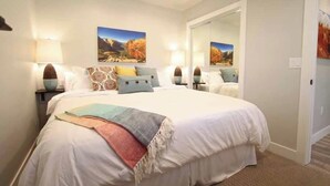 A bedroom with a large bed, two bedside tables, a mirror, and two wall-mounted lamps. - Tiny Home near Zion with Rooftop Stargazing Deck (Orderville)