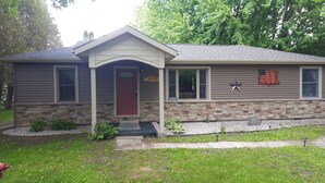 A two-story house with a stone foundation, a red front door, and a welcome sign. - Everything new in this beautiful secluded home. Air conditioning. Wifi. Firepit. (Lexington)