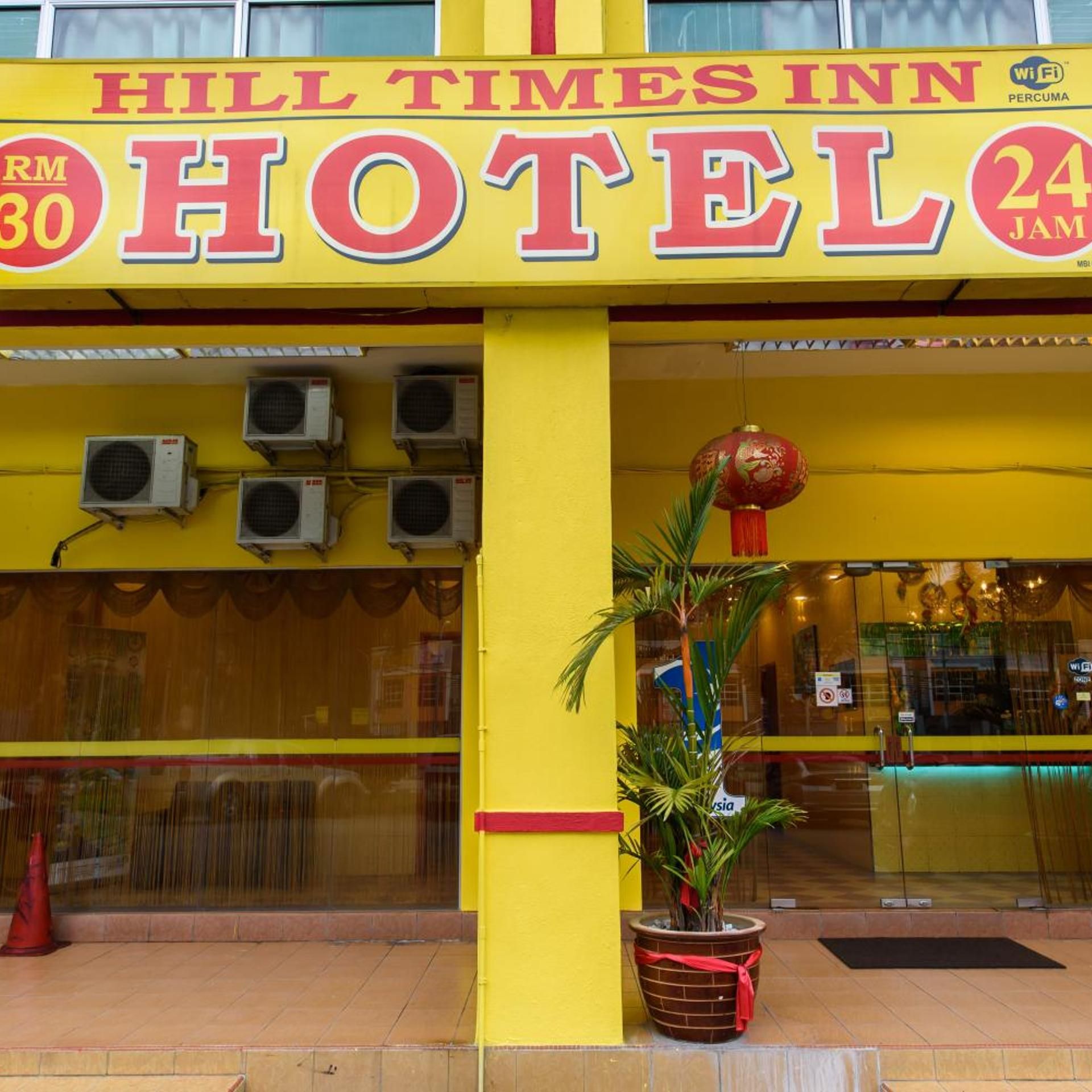 Een geel gebouw met een bord waarop staat 'Hill Times Inn Hotel'.