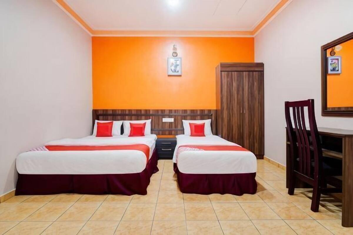 A room with two beds, a wooden headboard, a desk, and a chair.