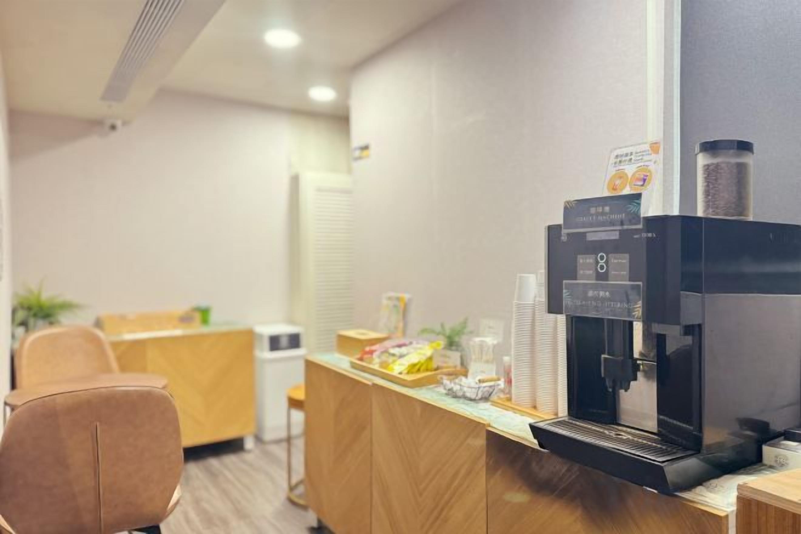 A reception area with a coffee machine, a counter, and a seating area.