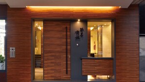 Fachada moderna de edificio con paneles de madera y acceso de vidrio.