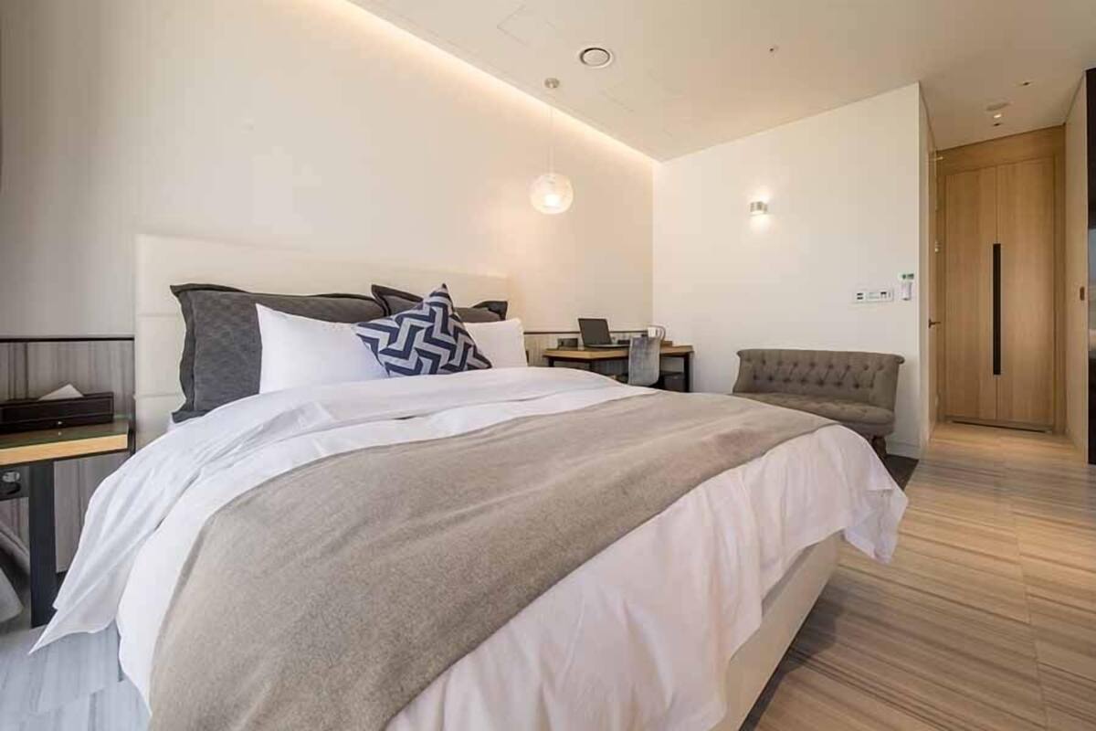 Ein modernes Hotelzimmer mit einem großen Bett, einem Schreibtisch, einem Stuhl und einem Kleiderschrank.