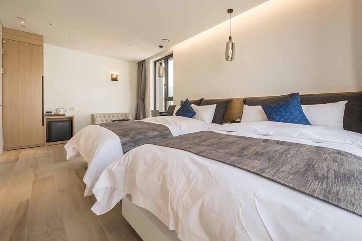 Ein modernes Hotelzimmer mit einem großen Bett, einem Nachttisch, einer Lampe und Blick auf die Stadt.