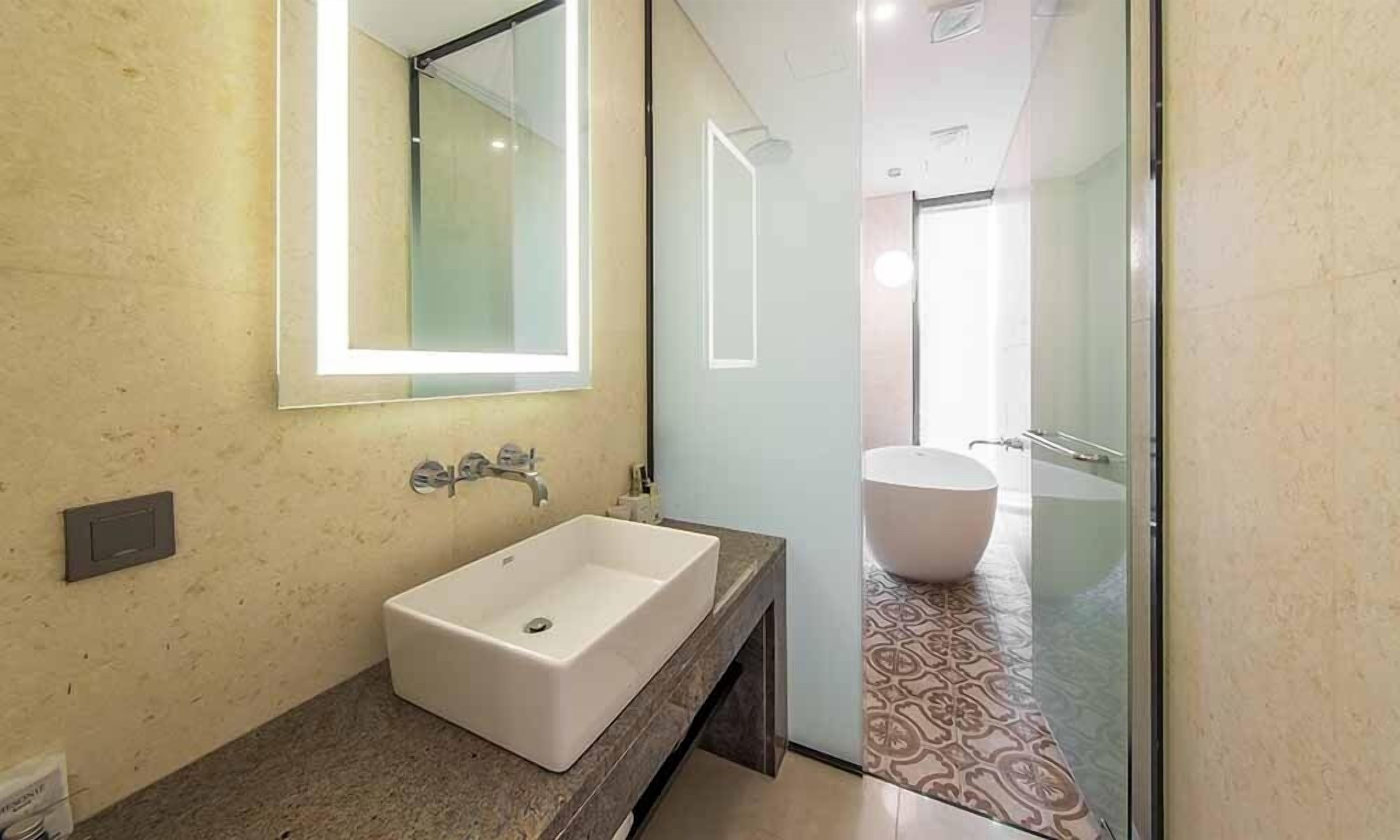A modern bathroom with a large rectangular sink, a mirror, and a separate bathtub.