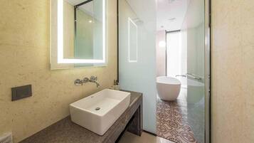 A modern bathroom with a large rectangular sink, a mirror, and a separate bathtub.