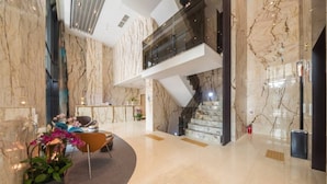 Eine moderne Lobby mit Marmorwänden, einer Treppe und einer Sitzecke mit einer Pflanze.
