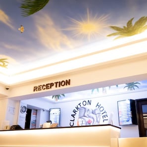A reception area with a sign reading 'RECEPTION' and 'CLARKTON HOTEL' above a counter. - Clarkton Hotel (Angeles City)