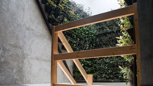 Une structure en bois avec un mur en béton et un jardin où poussent différentes espèces de plantes.
