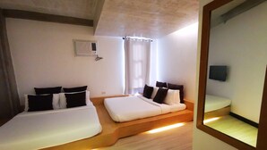 Une chambre d’hôtel avec deux lits, un téléviseur à écran plat fixé au mur et un système de climatisation intégré.